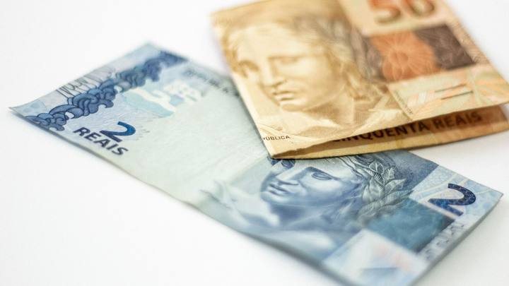 Cédulas de dois e cinquenta reais sobre fundo claro, vistas de perto.