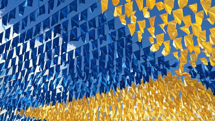 Bandeirinhas coloridas de festa junina esticadas contra o céu azul, tremulando ao vento.