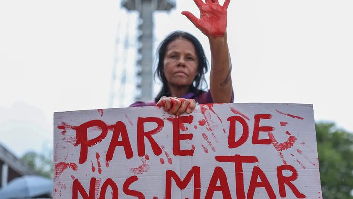 Mulher em manifestação segurando um cartaz branco com a frase 